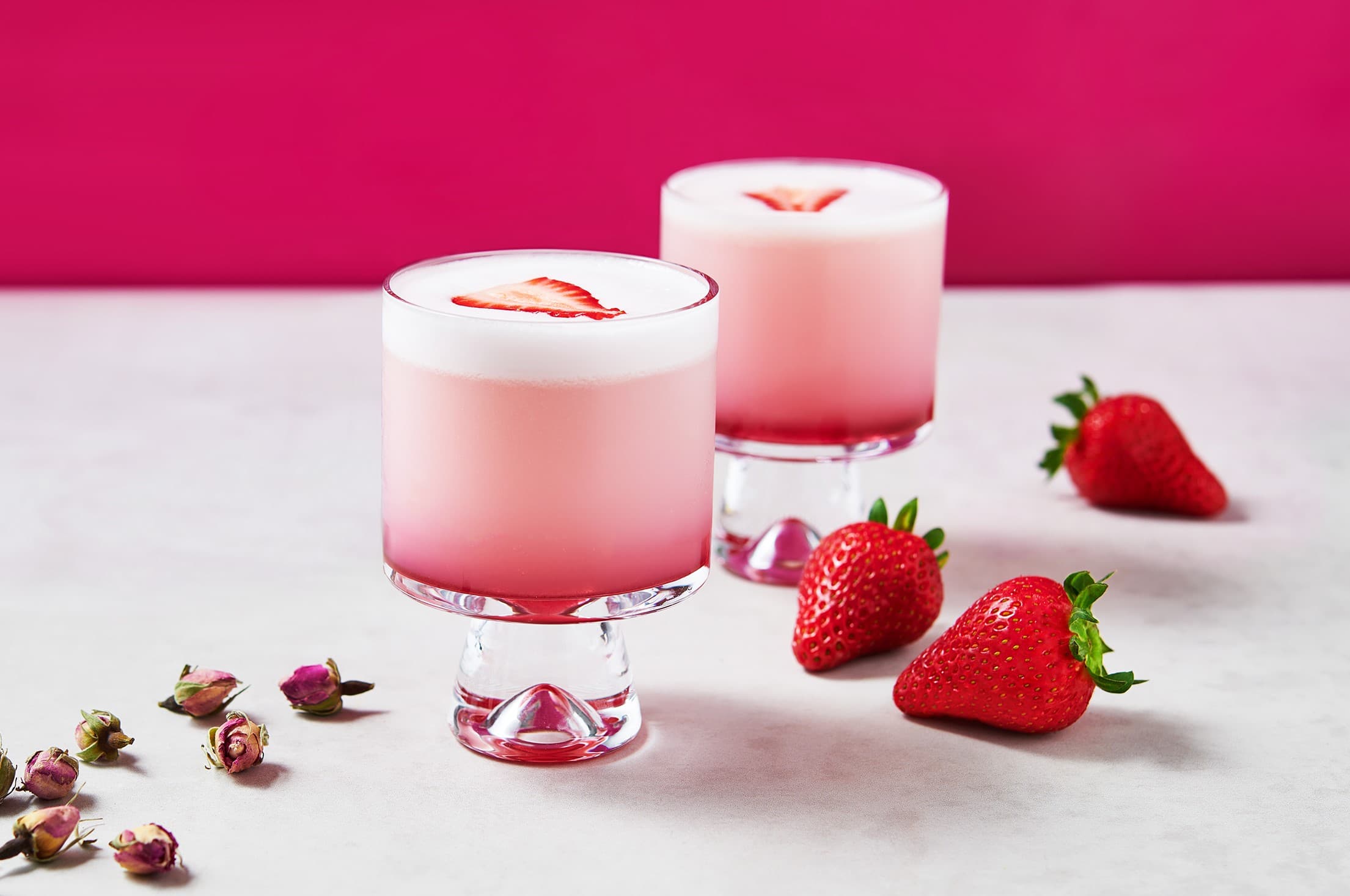 pink cocktail in a glass with strawberry garnish